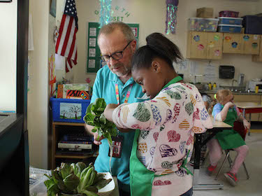 Student working with teacher on gardening